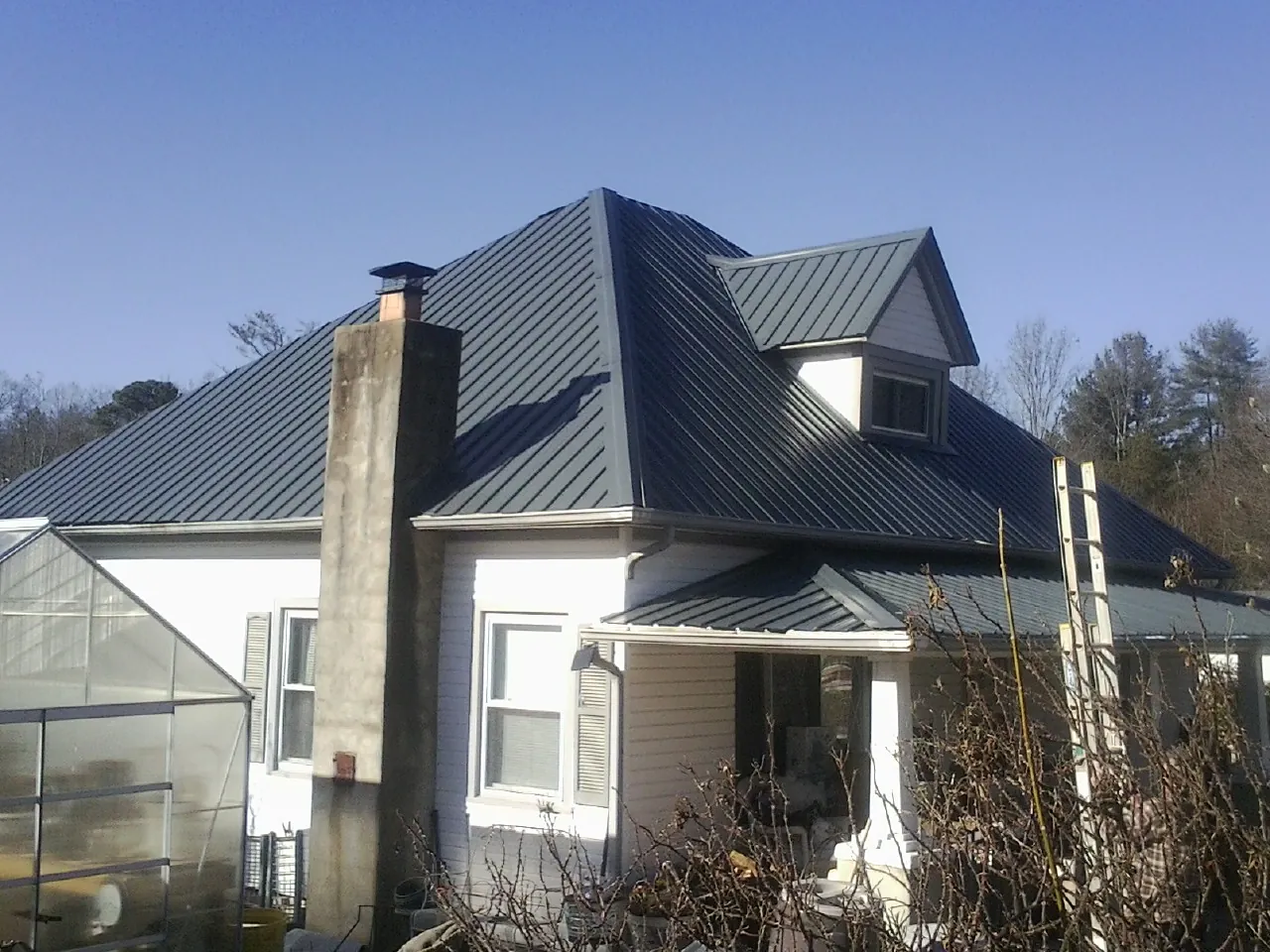 Dark blue standing seam metal roof on a white farmhouse with dormer — Slate & Tile Roof Repair by Roofing Brothers in Caseyville