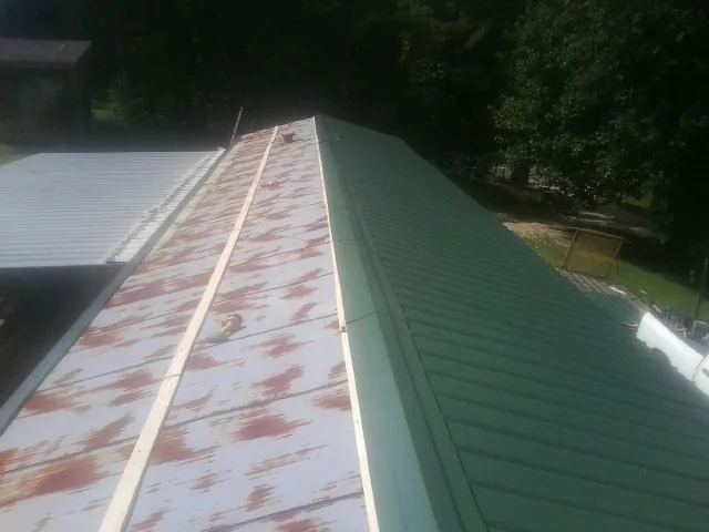 Old rusted panels beside newly installed green metal roofing — Wind Damage Roof Repair by Roofing Brothers in Caseyville