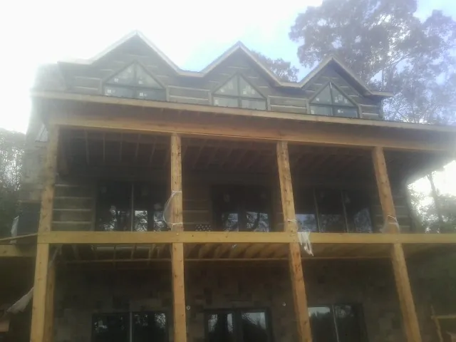 Dormers and porch framing on a large log home under construction — Roof Coating work by our crew in Caseyville