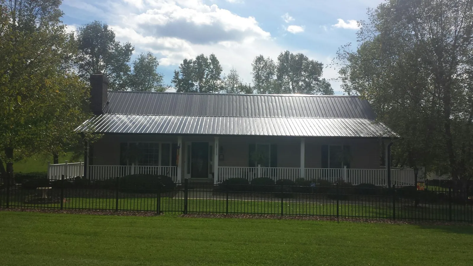 Gray metal roof on a brick ranch with a full width front porch — Gutter Guard Installation work by our crew in Caseyville