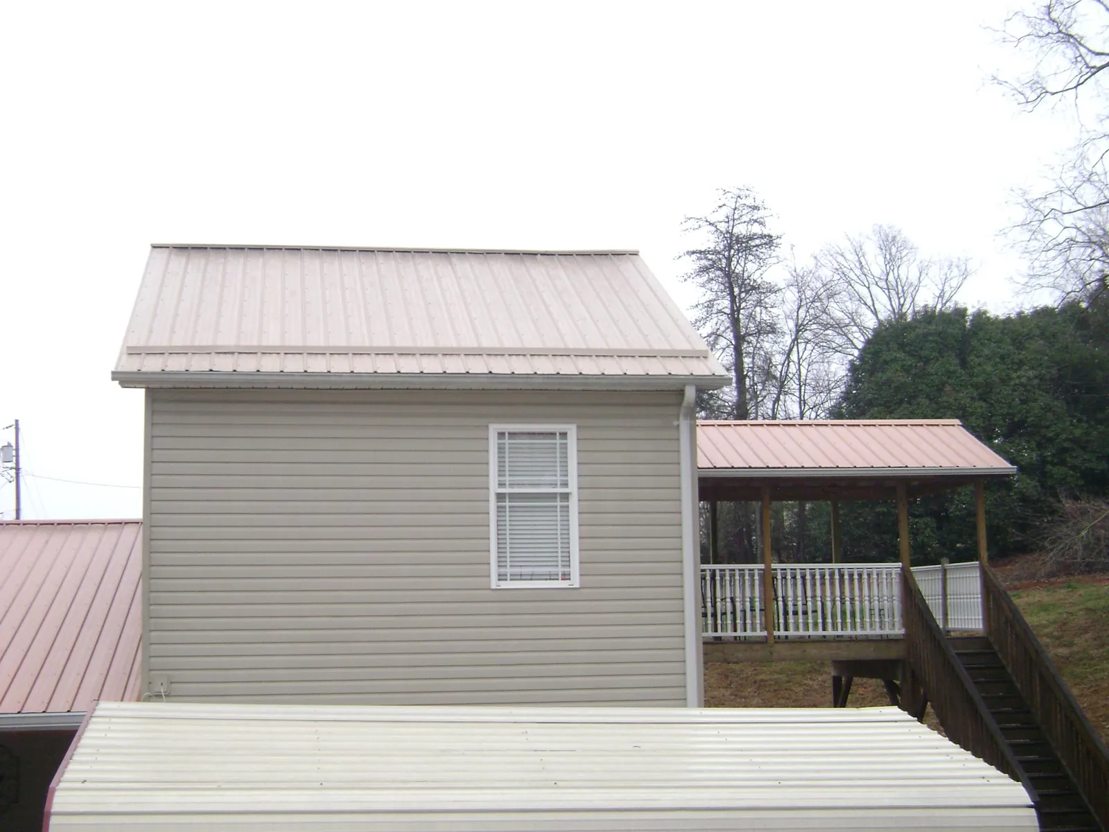 Tan metal roofs on a two story addition and attached porch, from a Roof Replacement job in Caseyville