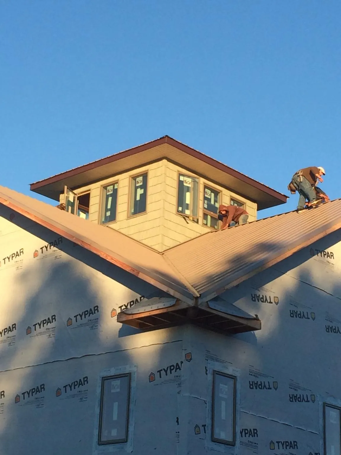 Roofers working around a rooftop cupola on a new metal roof at sunset — Roof Waterproofing in Caseyville by Roofing Brothers